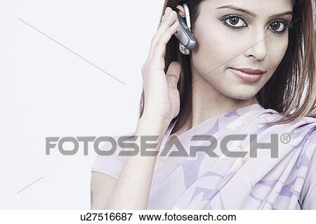 Stock Photo - Portrait of a young woman wearing a hands free device. Fotosearch