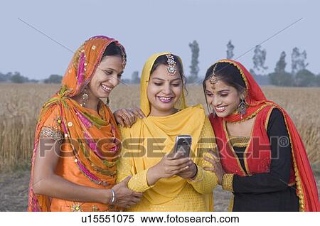 Stock Photography - Three young women looking at a mobile phone. Fotosearch