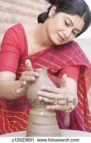 Stock Image - Close-up of a mid adult woman making a pottery. Fotosearch