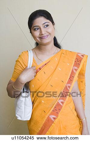 Mid adult woman carrying a bag on her shoulder and smiling View Large Photo Image Stock Photography - Mid adult woman carrying a bag on her shoulder and smiling. Fotosearch