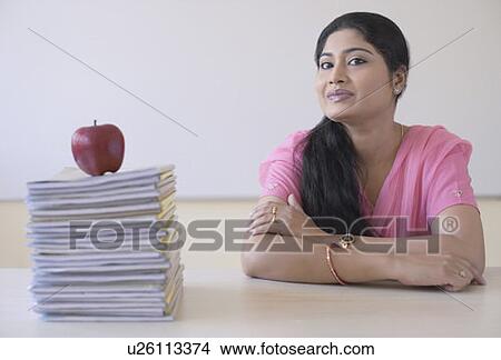 Portrait of a mid adult woman sitting at a desk with her arms crossed View Large Photo Image Picture - Portrait of a mid adult woman sitting at a desk with her arms crossed. Fotosearch