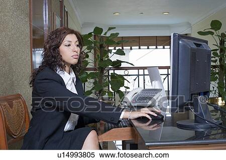 Side profile of a female receptionist working on a desktop PC in a hotel reception View Large Photo Image Stock Photography - Side profile of a female receptionist working on a desktop PC in a hotel reception. Fotosearch