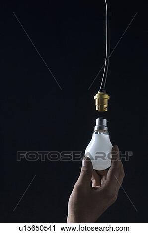 Stock Image - Close-up of a person's hand holding a light bulb. Fotosearch