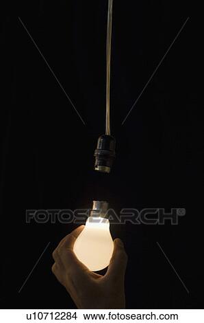 Close-up of a person's hand holding an illuminated light bulb View Large Photo Image Picture - Close-up of a person's hand holding an illuminated light bulb. Fotosearch