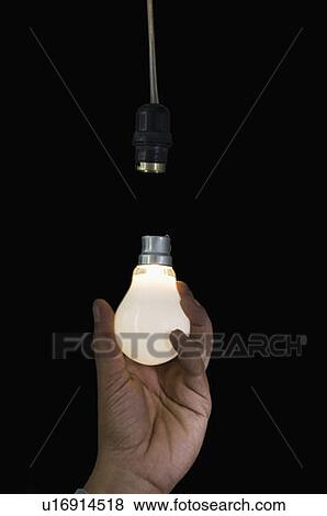Close-up of a person's hand holding an illuminated light bulb View Large Photo Image Stock Photo - Close-up of a person's hand holding an illuminated light bulb. Fotosearch