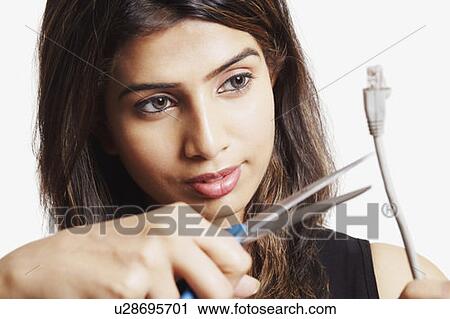 Stock Image - Close-up of a young woman cutting a network computer cable. Fotosearch