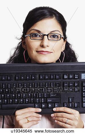 Portrait of a businesswoman holding a computer keyboard and smirking View Large Photo Image Stock Photography - Portrait of a businesswoman holding a computer keyboard and smirking. Fotosearch