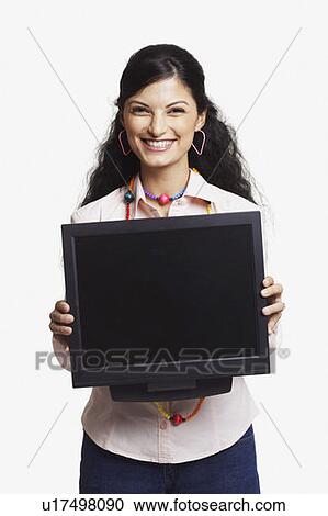 Portrait of a young woman holding a flat screen computer monitor and smiling View Large Photo Image Stock Image - Portrait of a young woman holding a flat screen computer monitor and smiling. Fotosearch