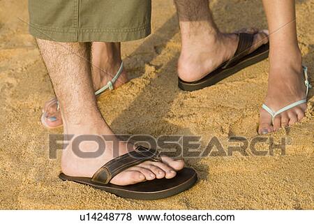 Low section view of a couple standing in sand View Large Photo Image Stock Photo - Low section view of a couple standing in sand. Fotosearch