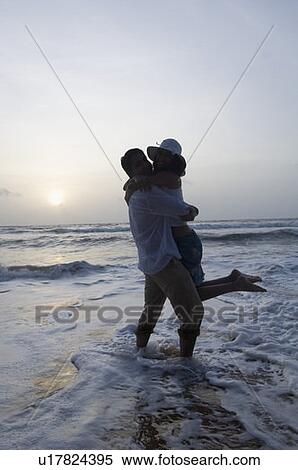 Stock Photography - Silhouette of a young couple romancing on the beach, Goa, India. Fotosearch