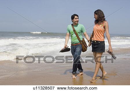Young couple walking on the beach with holding hands View Large Photo Image Stock Photo - Young couple walking on the beach with holding hands. Fotosearch