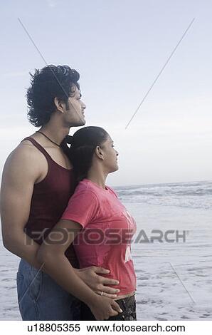 Young man embracing a young woman from behind on the beach View Large Photo Image Stock Photography - Young man embracing a young woman from behind on the beach. Fotosearch