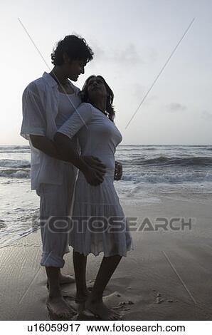 Young man embracing a young woman on the beach View Large Photo Image Stock Photo - Young man embracing a young woman on the beach. Fotosearch