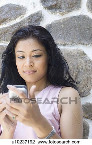 Stock Image - Close-up of a young woman using a mobile phone. Fotosearch