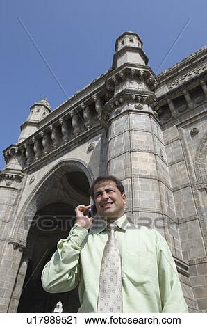 Low angle view of a businessman talking on a mobile phone and smiling, Gateway of India, Mumbai, Maharashtra, India View Large Photo Image Stock Image - Low angle view of a businessman talking on a mobile phone and smiling, Gateway of India, Mumbai, Maharashtra, India. Fotosearch