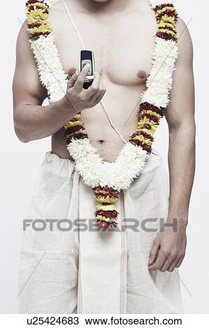 Stock Image - Mid section view of a young man holding a mobile phone. Fotosearch