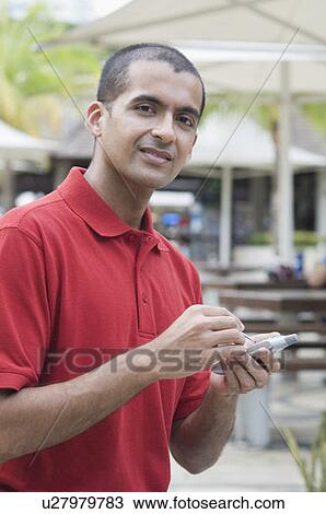 Portrait of a young man text messaging on a palmtop View Large Photo Image Stock Image - Portrait of a young man text messaging on a palmtop. Fotosearch