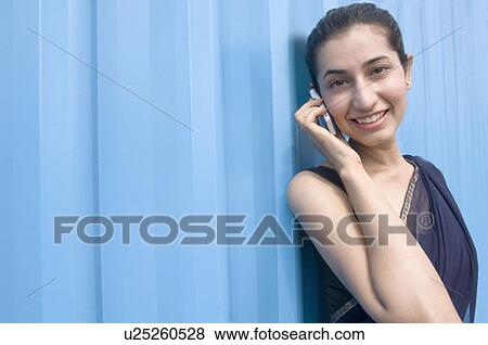 Stock Photo - Portrait of a young woman talking on a mobile phone and smiling . Fotosearch