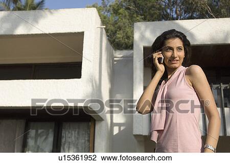 Side profile of a young woman talking on a mobile phone and smiling View Large Photo Image Stock Image - Side profile of a young woman talking on a mobile phone and smiling. Fotosearch
