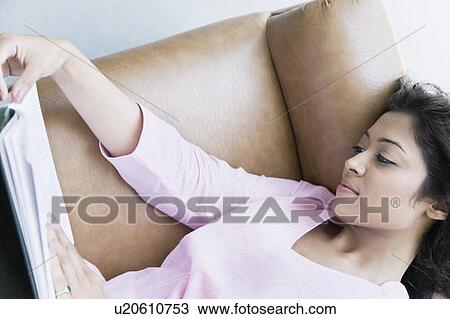 High angle view of a young woman lying on a couch and reading a book View Large Photo Image Stock Image - High angle view of a young woman lying on a couch and reading a book. Fotosearch