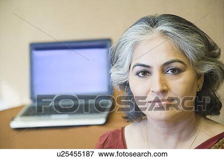 Stock Photo - Portrait of a businesswoman with a laptop in the background. Fotosearch