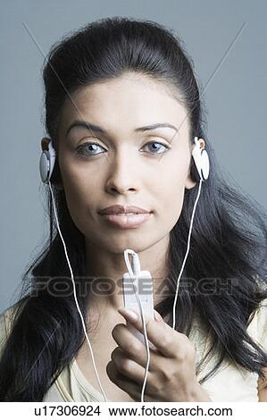 Picture - Portrait of a young woman listening to an MP3 player. Fotosearch