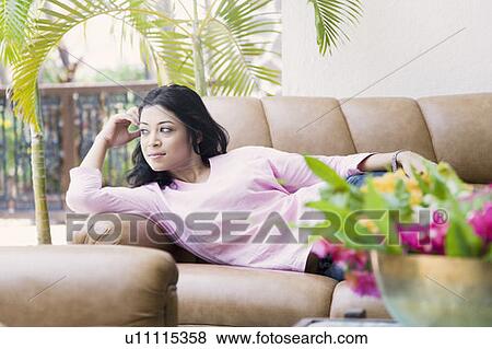 Young woman lying on a couch and thinking View Large Photo Image Stock Photo - Young woman lying on a couch and thinking. Fotosearch