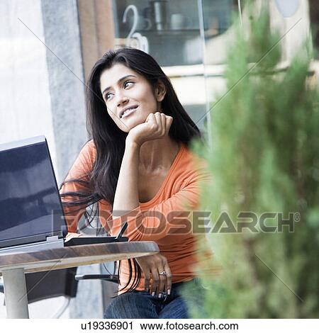 Stock Image - Young woman sitting in a restaurant. Fotosearch