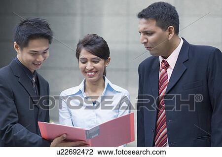 Businesswoman holding a file with two businessmen and smiling View Large Photo Image Stock Image - Businesswoman holding a file with two businessmen and smiling. Fotosearch