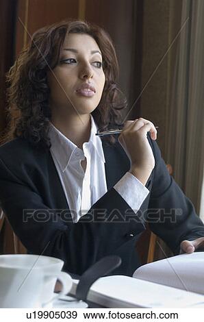 Stock Photo - Businesswoman holding a pen and thinking. Fotosearch