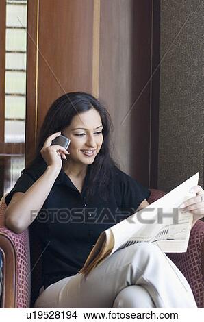 Picture - Businesswoman sitting in an armchair and talking on a mobile phone. Fotosearch