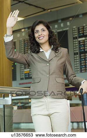 Businesswoman waving her hand at an airport View Large Photo Image Stock Image - Businesswoman waving her hand at an airport. Fotosearch