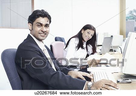 Picture - Portrait of a businessman and a businesswoman sitting in an office. Fotosearch