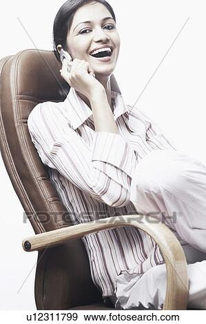Stock Photo - Portrait of a businesswoman sitting on a chair talking on a mobile phone. Fotosearch
