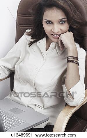 Portrait of a businesswoman with a laptop on her lap sitting on an office chair View Large Photo Image Stock Image - Portrait of a businesswoman with a laptop on her lap sitting on an office chair. Fotosearch