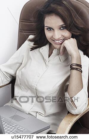 Portrait of a businesswoman with a laptop on her lap sitting on an office chair View Large Photo Image Stock Photo - Portrait of a businesswoman with a laptop on her lap sitting on an office chair. Fotosearch