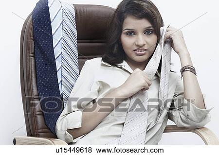 Portrait of a businesswoman with a tie in her hand sitting on an office chair View Large Photo Image Stock Photo - Portrait of a businesswoman with a tie in her hand sitting on an office chair. Fotosearch
