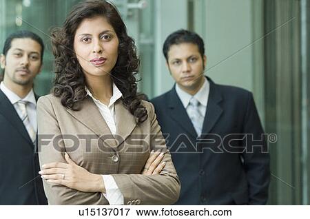 Stock Photo - Portrait of a businesswoman with two businessmen standing behind her. Fotosearch