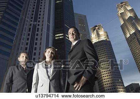 Portrait of two businessmen standing with a businesswoman with skyscrapers in the background, Singapore View Large Photo Image Picture - Portrait of two businessmen standing with a businesswoman with skyscrapers in the background, Singapore. Fotosearch