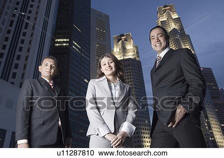 Portrait of two businessmen standing with a businesswoman with skyscrapers in the background, Singapore View Large Photo Image Stock Image - Portrait of two businessmen standing with a businesswoman with skyscrapers in the background, Singapore. Fotosearch