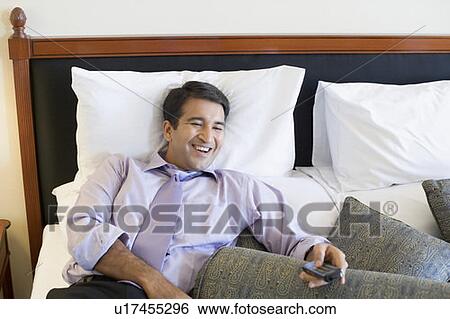Stock Photograph - Businessman holding a remote control and smiling. Fotosearch