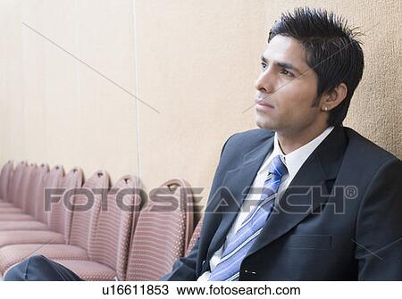 Stock Image - Close-up of a businessman sitting on a chair and thinking. Fotosearch