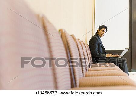 Stock Image - Portrait of a businessman working on a laptop in a conference room. Fotosearch