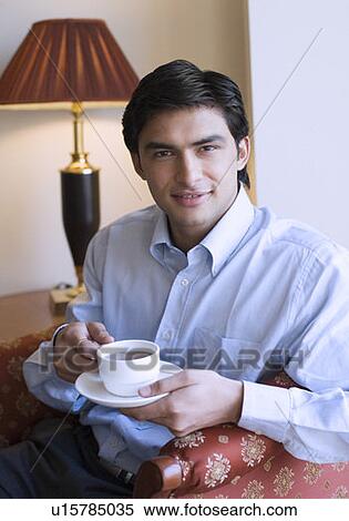 Portrait of a young man holding a cup of tea and smiling View Large Photo Image Stock Photography - Portrait of a young man holding a cup of tea and smiling. Fotosearch