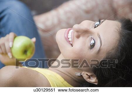 Portrait of a young woman holding a granny smith apple and smiling View Large Photo Image Stock Image - Portrait of a young woman holding a granny smith apple and smiling. Fotosearch