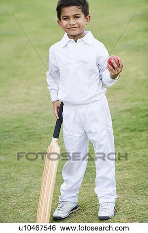 Stock Photograph - Boy holding a cricket bat and a cricket ball. Fotosearch