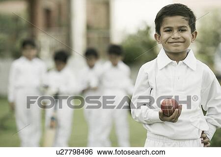 Stock Photograph - Cricketer holding a cricket ball and smiling. Fotosearch