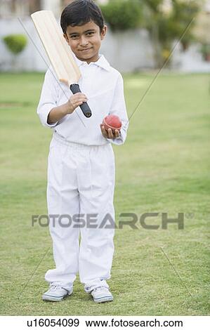 Stock Photo - Portrait of a boy holding a cricket bat and a cricket ball. Fotosearch