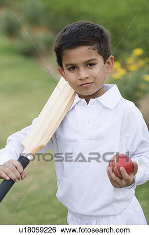 Stock Photograph - Portrait of a boy holding a cricket bat and a cricket ball. Fotosearch