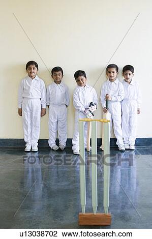 Stock Image - Portrait of five boys standing behind cricket stumps. Fotosearch